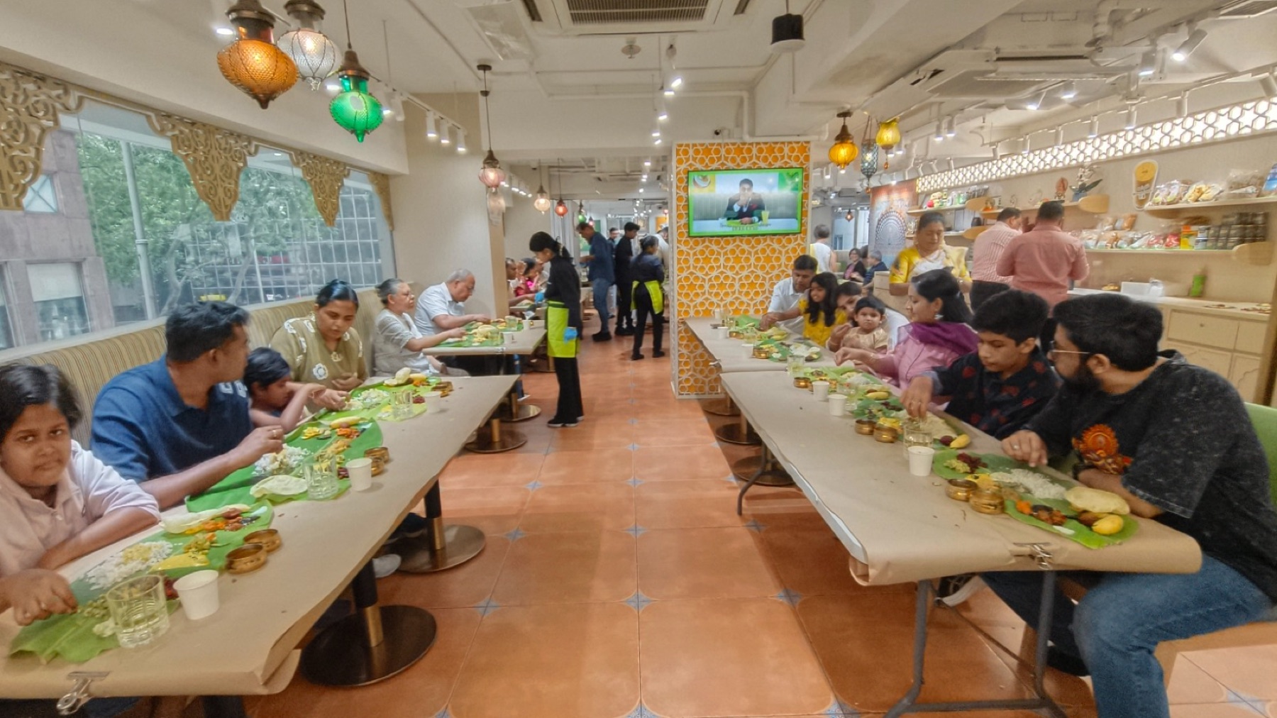 Guests seated at long tables eating Onam Sadhya on banana leaves at Woodlands Wan Chai